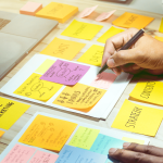 A man writing on sticky notes with thoughts about marketing